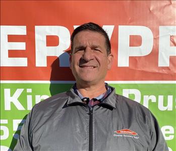 Male Employee Standing in front of SERVPRO Banner 