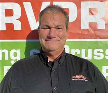 Male Employee Standing in front of SERVPRO Banner 