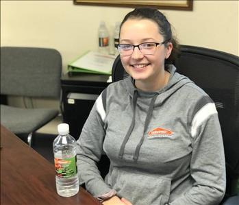 Female Employee with brown hair looking at camera at her desk 